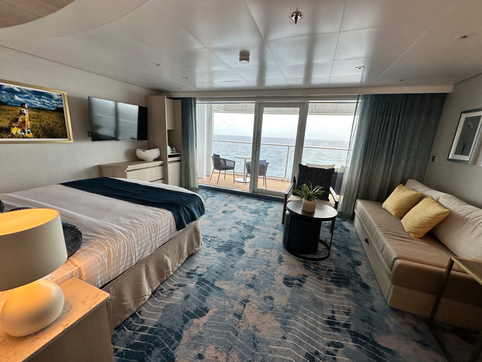 A spacious ocean-view balcony stateroom on Icon of the Seas with a king bed, sofa and sliding glass door. Photo: Dreams Fulfilled Travel Dream Designer